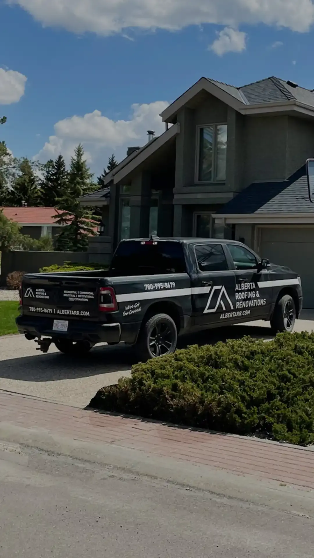 Two-storey Edmonton home with a new dark shingle roof and the Alberta Roofing & Renovations truck in the driveway