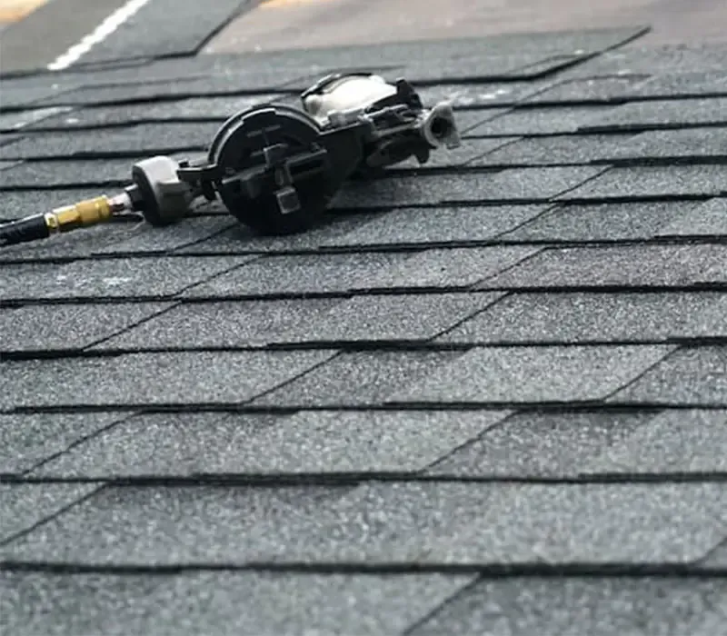Roofing nailer resting on new asphalt shingles