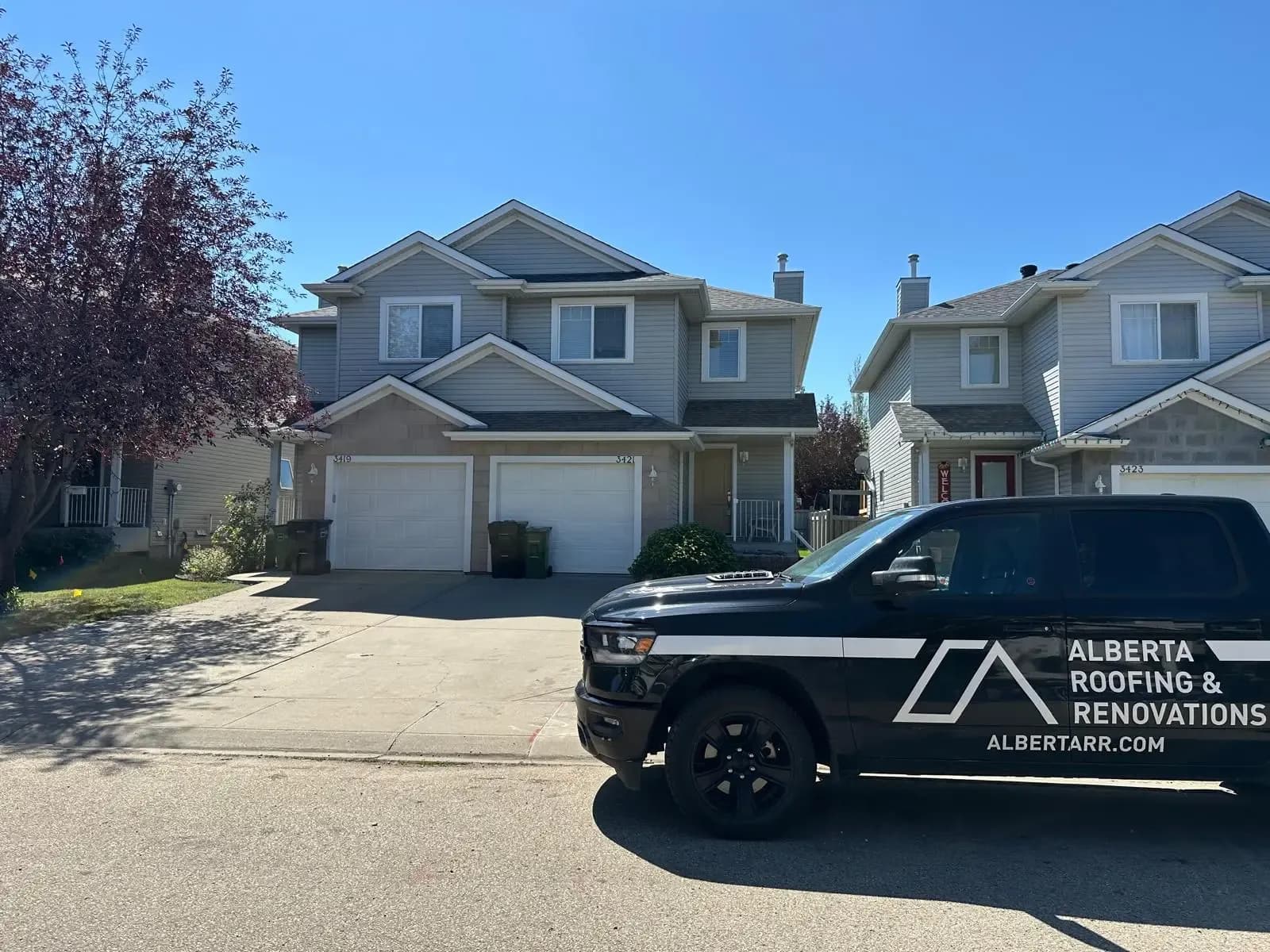 Alberta Roofing & Renovations truck in front of a duplex after a roof replacement